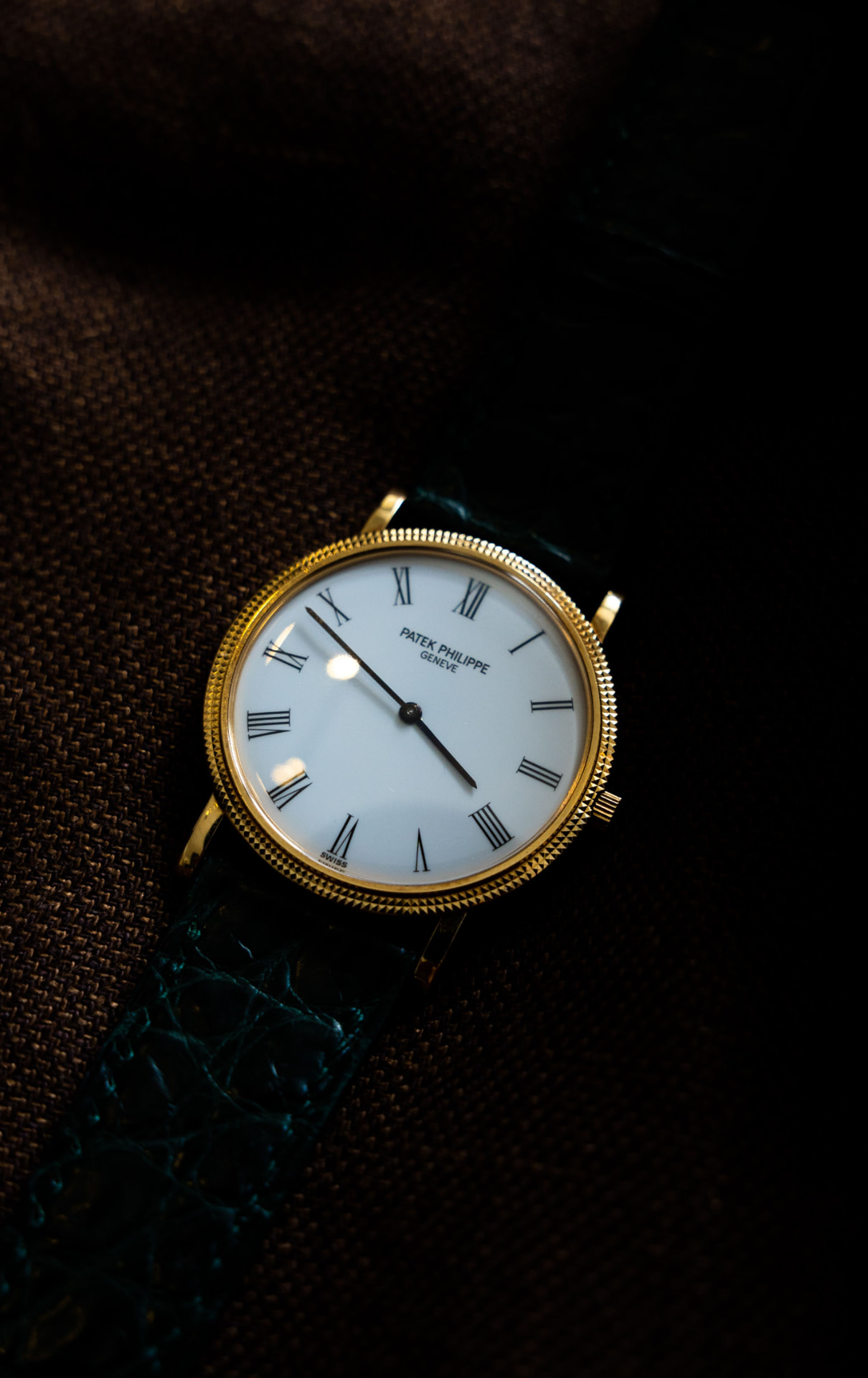 Vintage stainless steel sports watch with black dial resting on dark leather